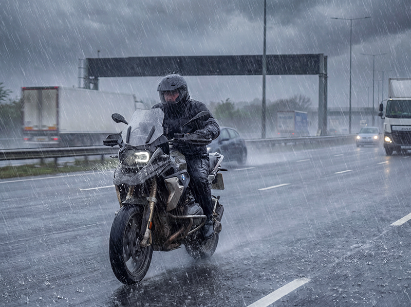 Man riding BMW GS motorcycle in extreme rain on UK motorway